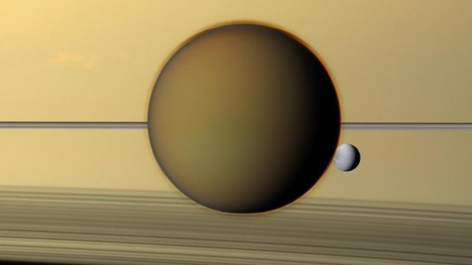 Titan nähtynä Saturnuksen pintaa vasten, mukana myös pienempi kuu Dione